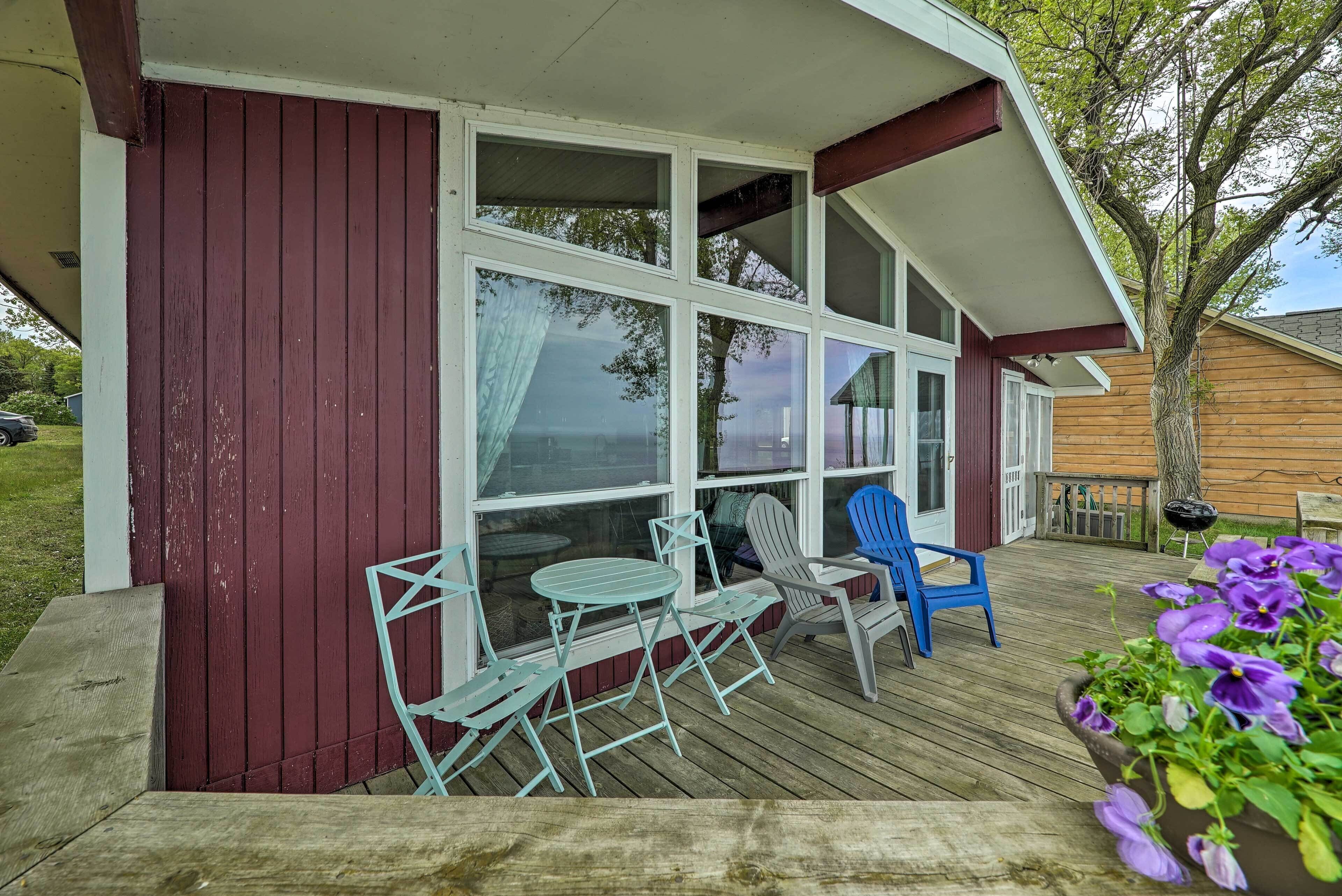 A covered patio with a table and chairs, a wooden deck, and a potted plant with purple flowers.