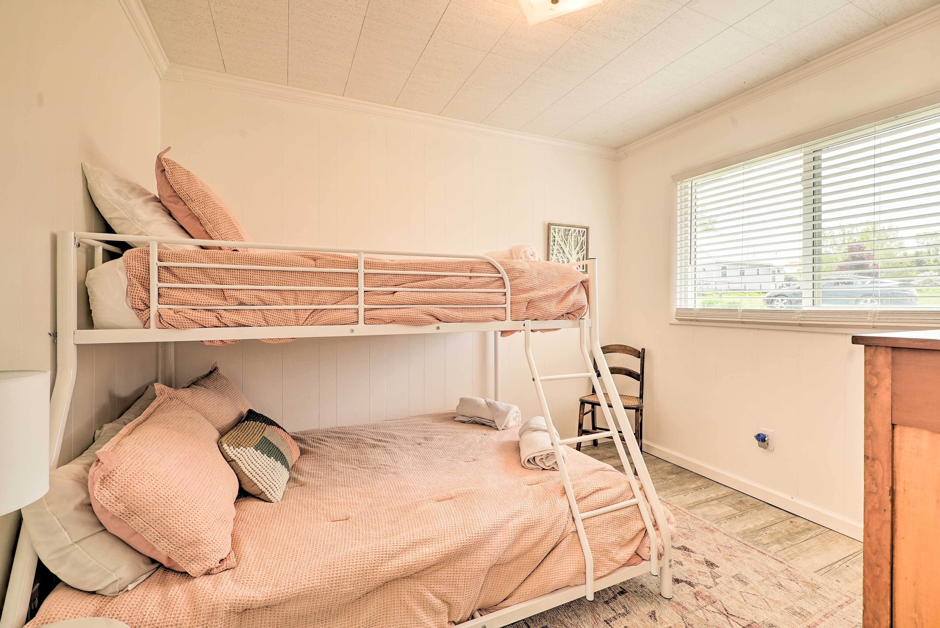 Une chambre avec un lit superposé, une fenêtre, une chaise et un bureau.