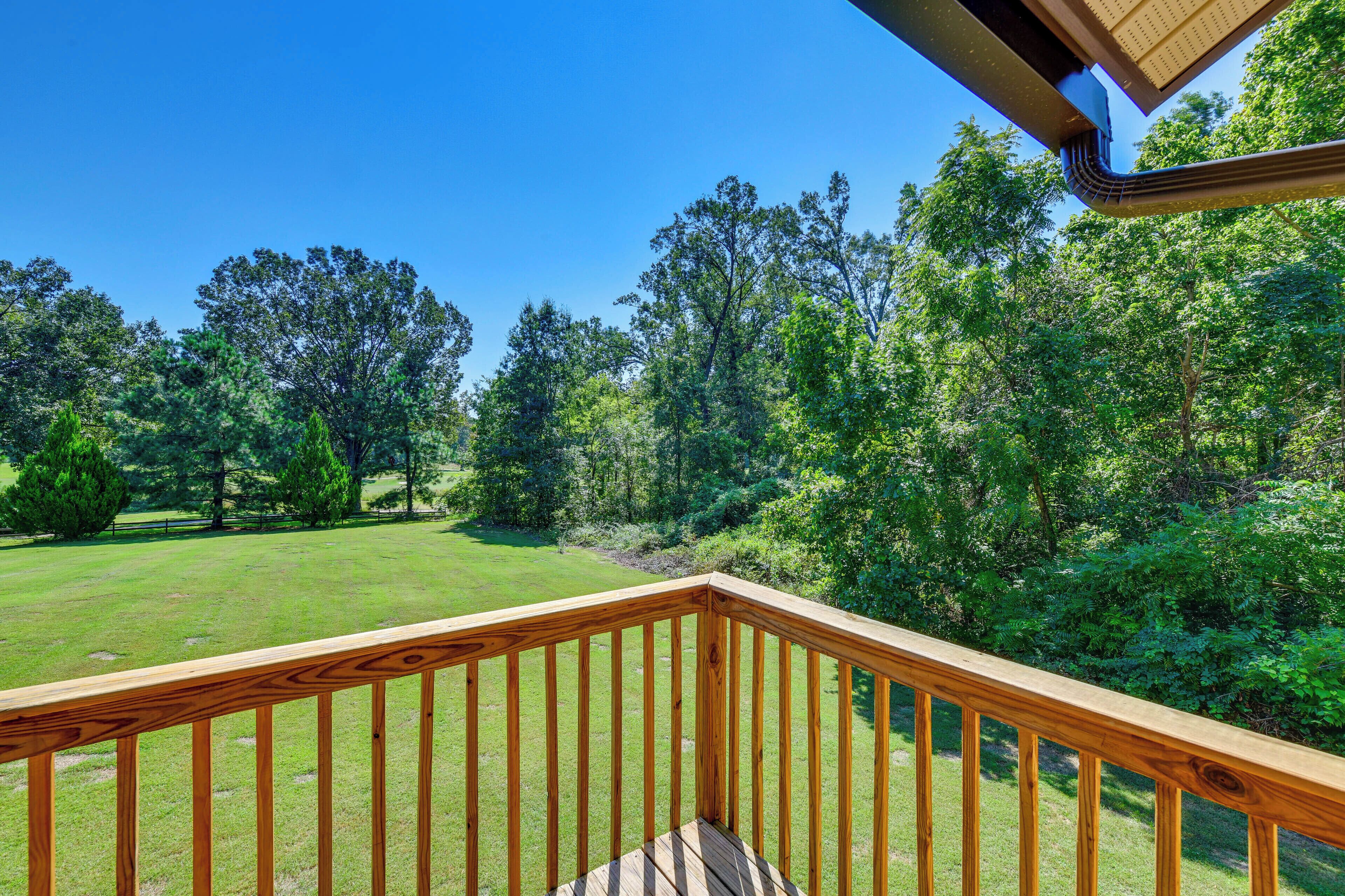 A wooden deck with a view of a grassy area and trees.