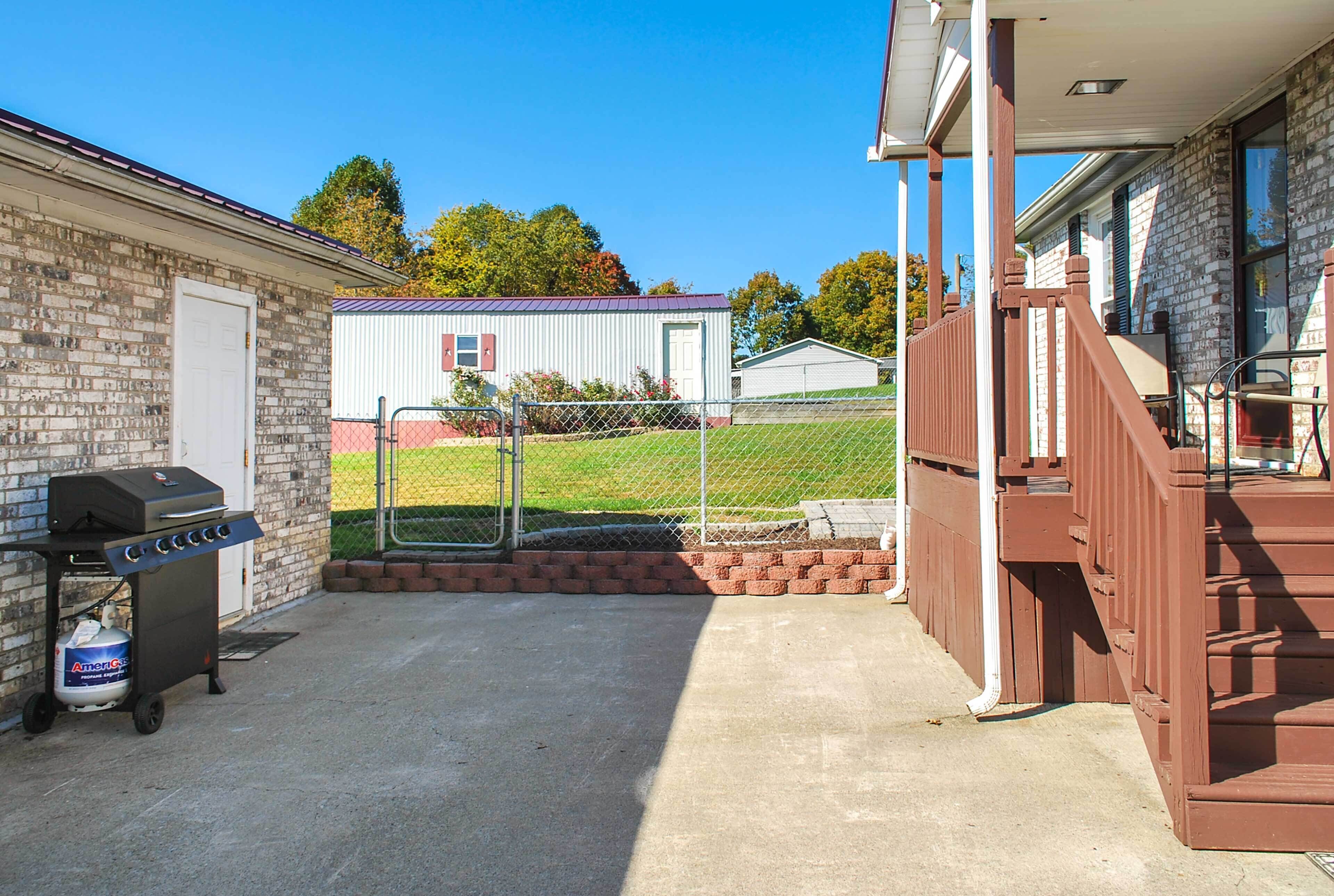 A patio area with a grill, a covered seating area, and a brick wall.