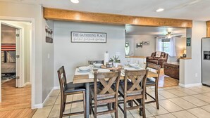 Un coin repas avec une table en bois dressée pour quatre personnes, entourée de chaises en bois. Une pancarte sur le mur indique : « Lieu de rencontre ».