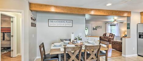 Ein Essbereich mit einem Holztisch, gedeckt für vier Personen, umgeben von Holzstühlen. Ein Schild an der Wand trägt die Aufschrift 'THE GATHERING PLACE'.