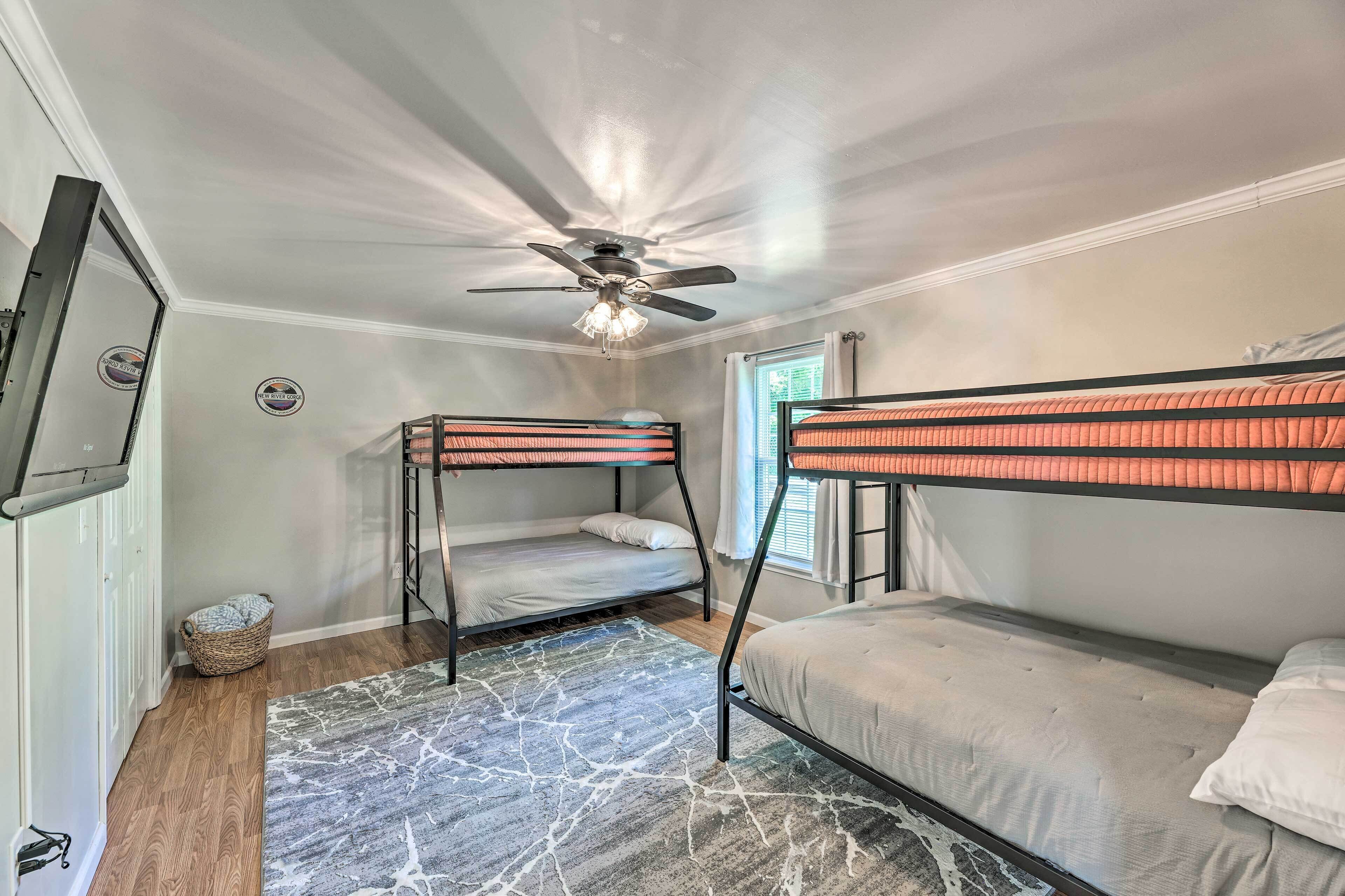 A room with two bunk beds, a ceiling fan, and a window with curtains.