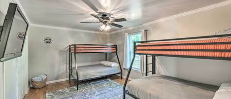 A room with two bunk beds, a ceiling fan, and a window with curtains.