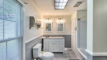 A bathroom with a toilet, sink, vanity, and shower.