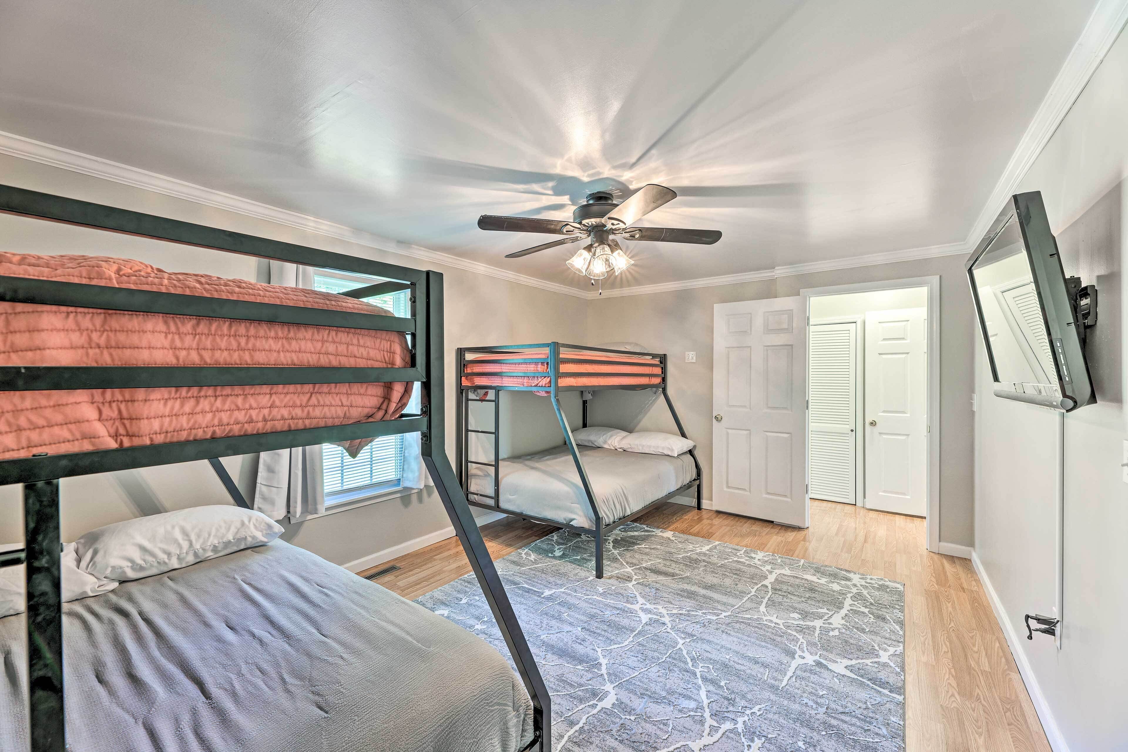 A room with bunk beds, a ceiling fan, a door, and a window.