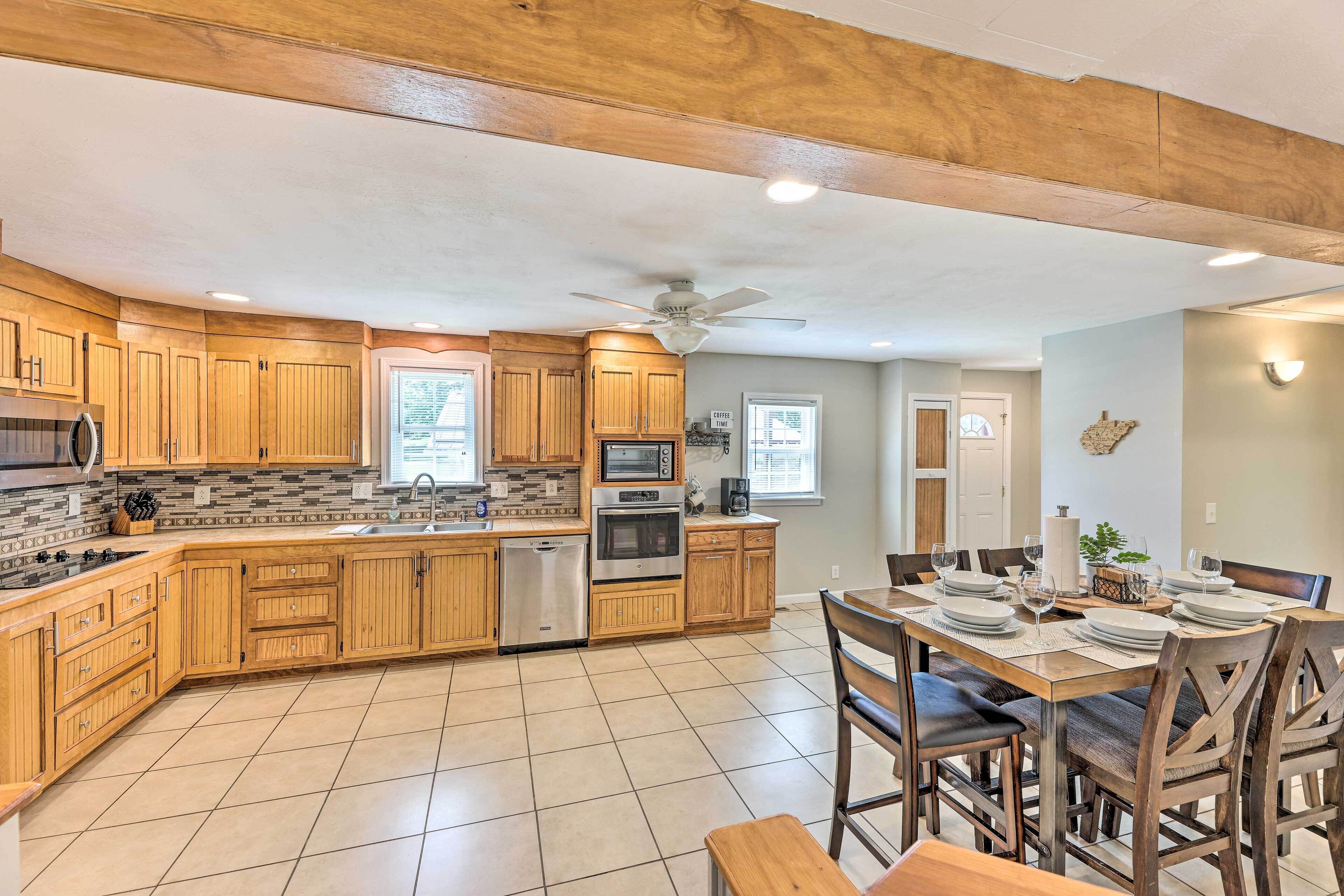A modern kitchen with wooden cabinets, stainless steel appliances, and a dining area with a table set for four.