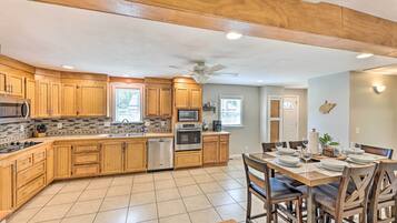 A modern kitchen with wooden cabinets, stainless steel appliances, and a dining area with a table set for four.