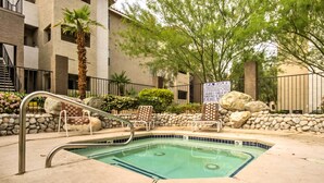 A swimming pool with a checkered lounge chair, a palm tree, and a stone wall. - Convenient Las Vegas Condo: 1 Mile to the Strip! (Las Vegas)