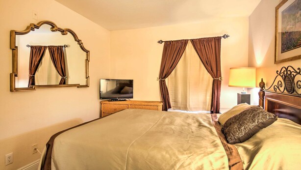 A hotel room with a large bed, a television on a wooden side table, and a painting on the wall. - Convenient Las Vegas Condo: 1 Mile to the Strip! (Las Vegas)