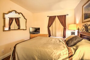 Ein Hotelzimmer mit einem großen Bett, einem Fernseher auf einem Holznachttisch und einem Gemälde an der Wand.