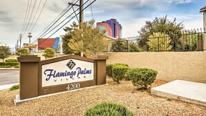 A sign for Flamingo Palm Villas with a clear view of the surrounding area, including a building in the background and a fenced property. - Convenient Las Vegas Condo: 1 Mile to the Strip! (Las Vegas)