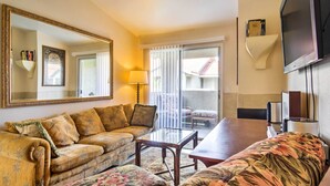 A living room with a sofa, a coffee table, and a television. There is a sliding glass door leading to an outdoor area. - Convenient Las Vegas Condo: 1 Mile to the Strip! (Las Vegas)
