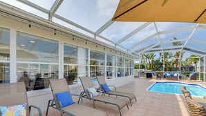 A covered outdoor area with lounge chairs and a pool. - Canal-front Haven: Pool, Dock & Lanai in Palmetto (Palmetto)