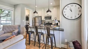 A modern kitchen with pendant lighting, a large wall clock, and a seating area with a sofa and chairs. - 12 Mi to Tcu: Fort Worth Cottage w/ Farmland Views (Fort Worth)