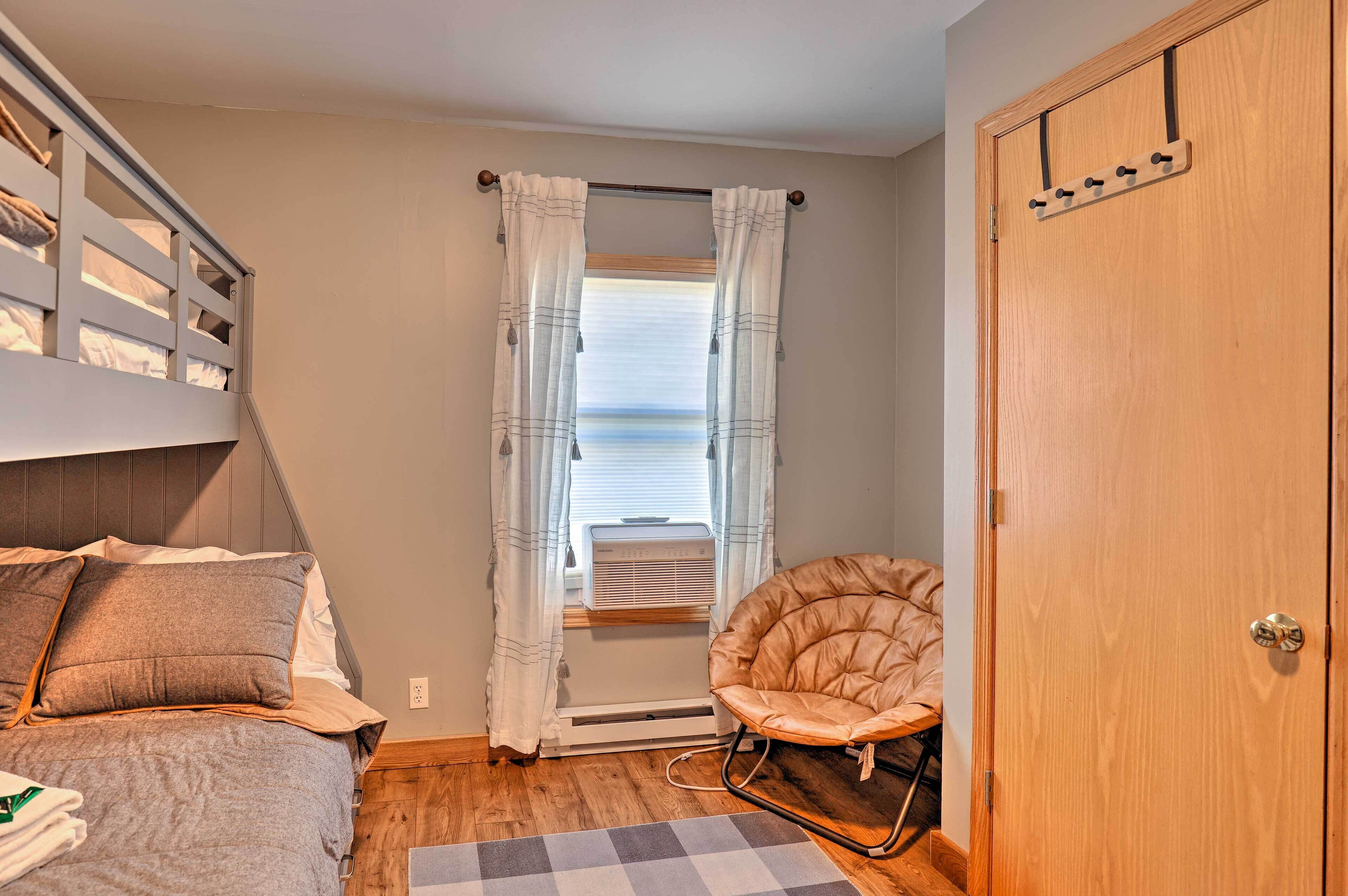 Une chambre à coucher avec un lit, une chaise, une armoire et une fenêtre avec des rideaux.