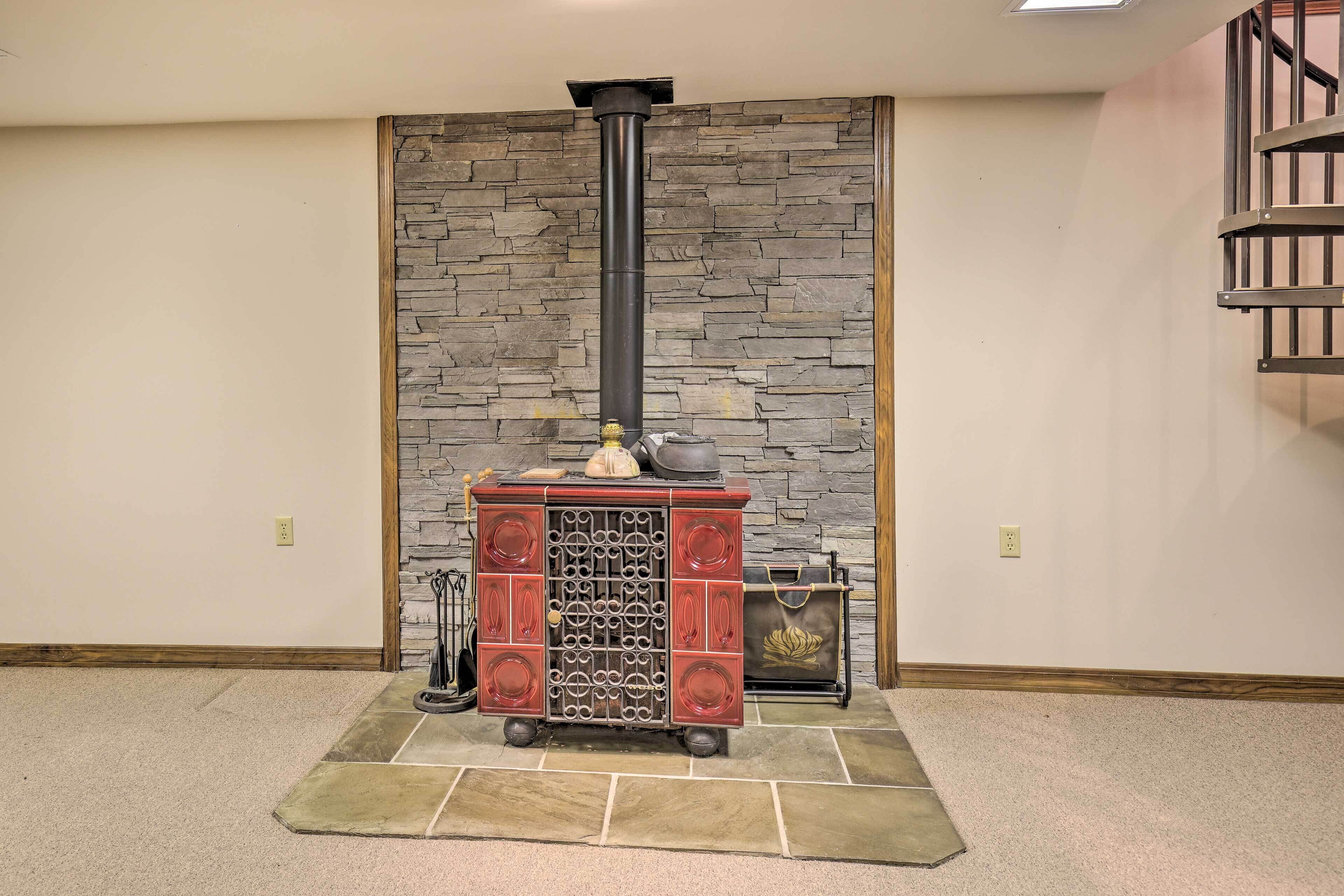A room with a stone wall, a fireplace with a chimney, and a wooden staircase.