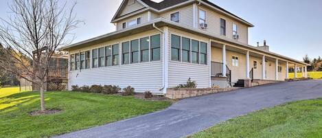 A two-story house with a covered porch, large windows, and a driveway.