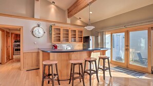 A kitchen with wooden cabinets, a bar area with stools, and a large window. - Lakefront Romulus Retreat w/ Private Dock! (Romulus)