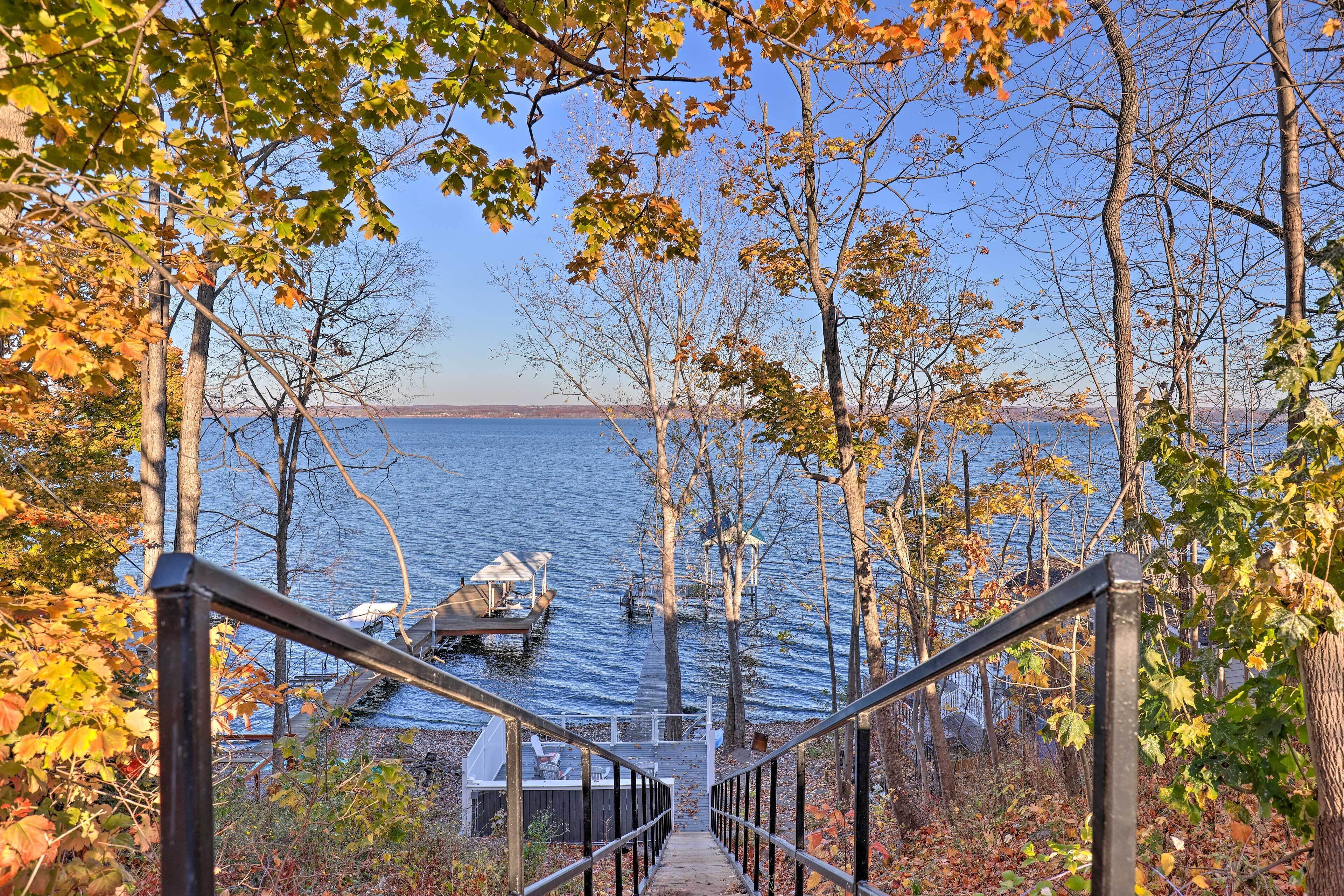 A wooden staircase leading to a dock by a lake with autumn foliage.