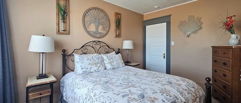 A bedroom with a bed, two bedside tables with lamps, a dresser, and decorative wall art.