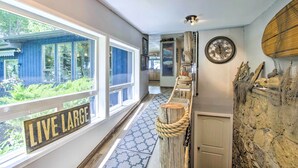 Een hal met een bord waarop 'Live Large' staat, een houten touwbarrière, een stenen muur met een mand aan een plank en een klok.