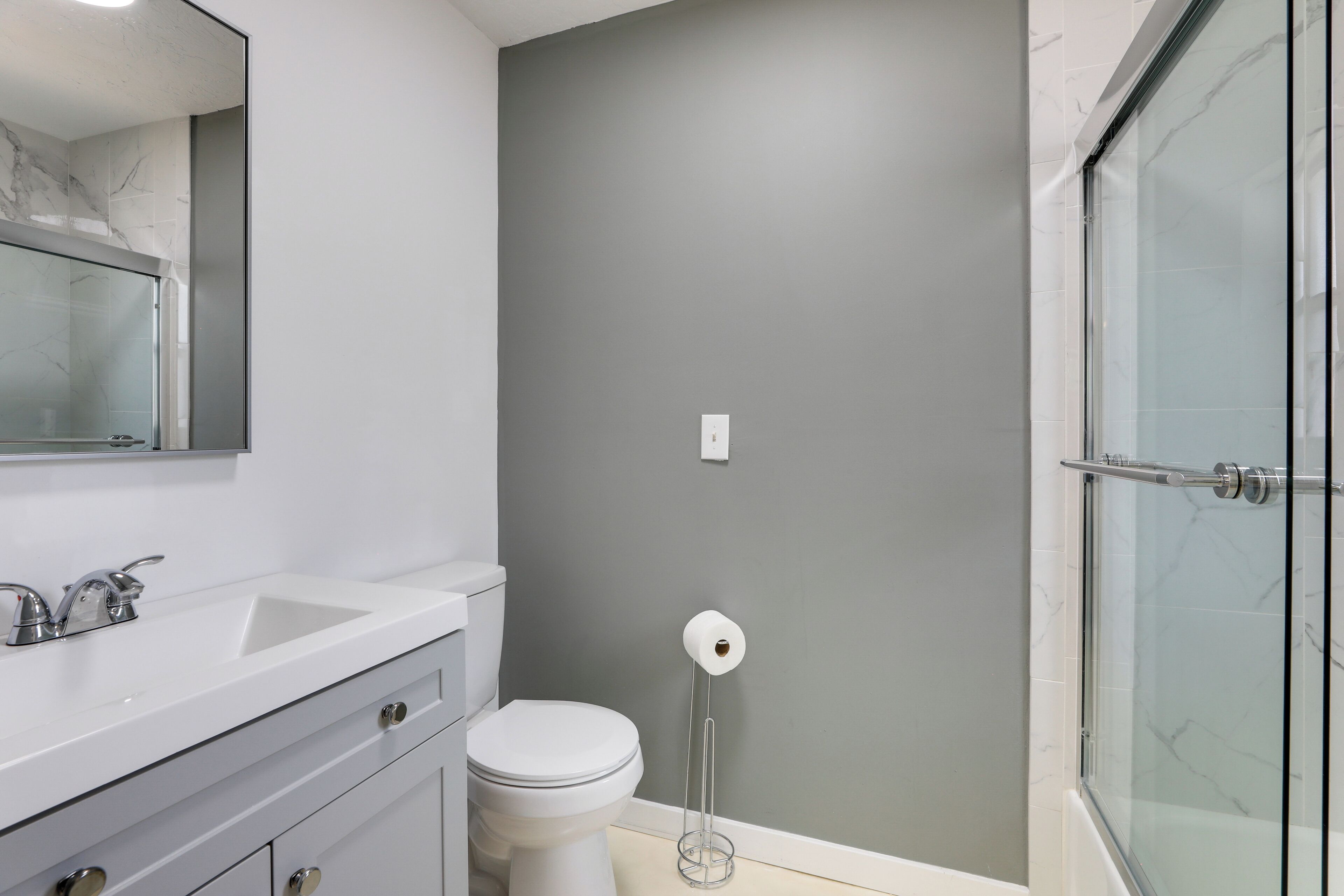 Une salle de bain avec un lavabo blanc, des toilettes et une cabine de douche en verre.