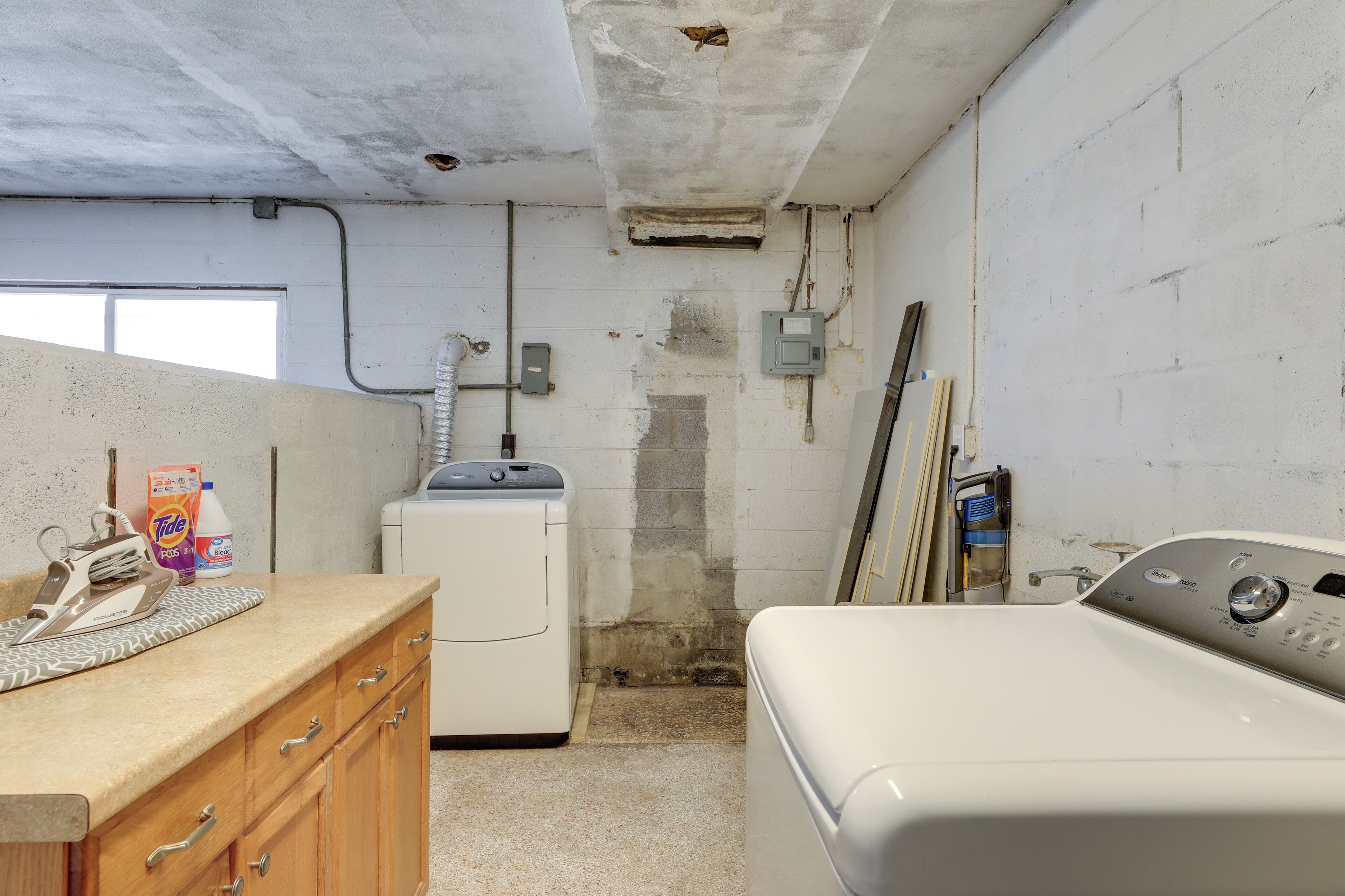 A laundry room with a washing machine, dryer, and ironing board.