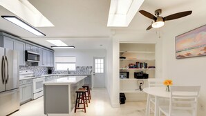 A modern kitchen with a central island, bar stools, a dining table with chairs, and a ceiling fan. - Dog-friendly Home w/ Patio & BBQ in Bradenton (Bradenton)