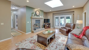 A living room with a fireplace, a sofa, a coffee table, and a TV. - Bella Vista Home w/ Kayaks & Deck on Loch Lomond! (Bella Vista)