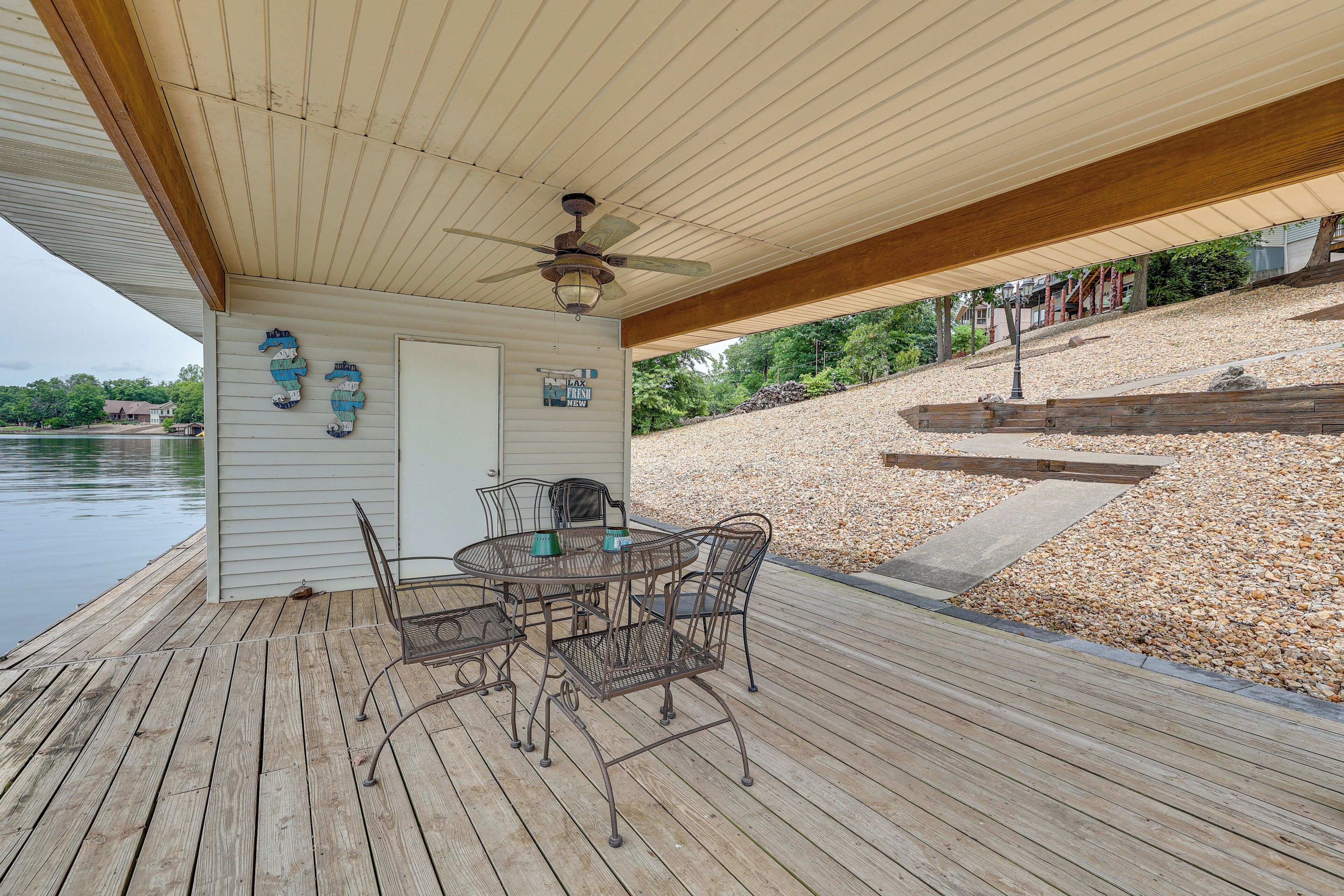 A wooden deck with a table and chairs, a ceiling fan, and decorative wall art.