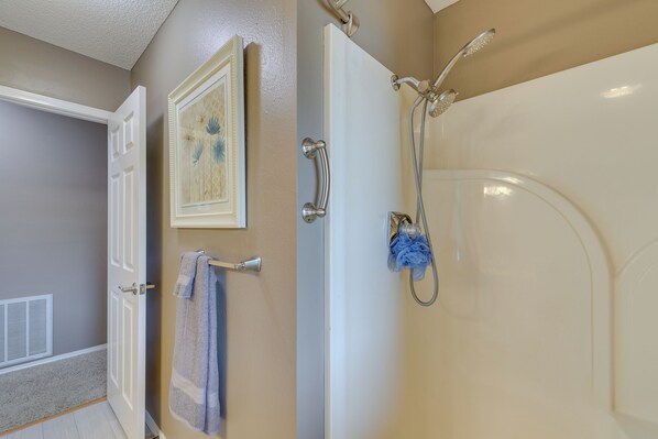 A bathroom with a bathtub, a shower, and a towel rack.