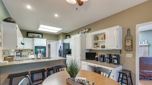 A modern kitchen with white cabinets, a dining area with a wooden table, and a living area with a brown leather couch. - Bella Vista Home w/ Kayaks & Deck on Loch Lomond! (Bella Vista)