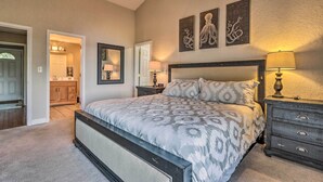 A bedroom with a large bed, a dresser, a nightstand, and a mirror. There is a door leading to a bathroom. - 1 Mi to Margaritaville! Cabin w/ Resort Perks (Osage Beach)
