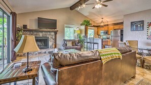 A spacious living room with a leather sofa, a fireplace, and a television mounted on the wall. - 1 Mi to Margaritaville! Cabin w/ Resort Perks (Osage Beach)