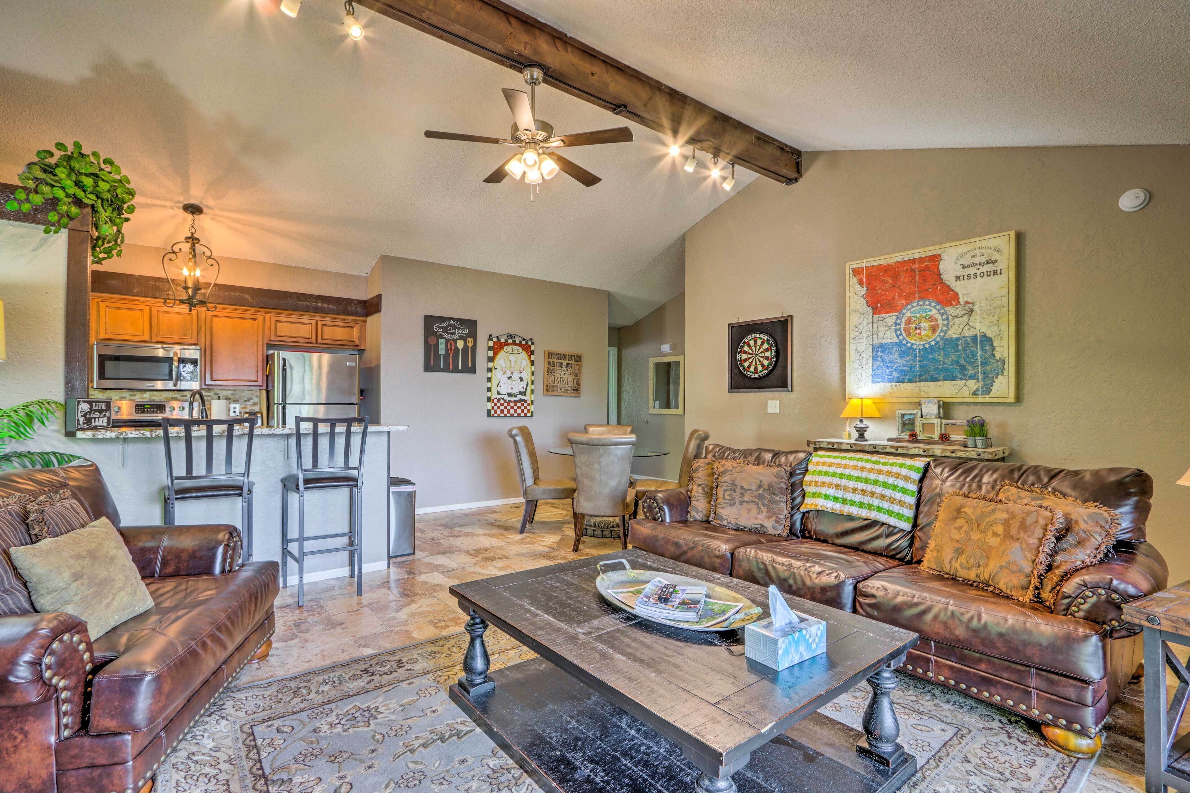 A spacious living room with a leather sofa, a coffee table, and a dining area with a bar.