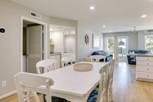 A modern kitchen with white cabinetry, a dining table with chairs, and a large window with a view of the outdoors.