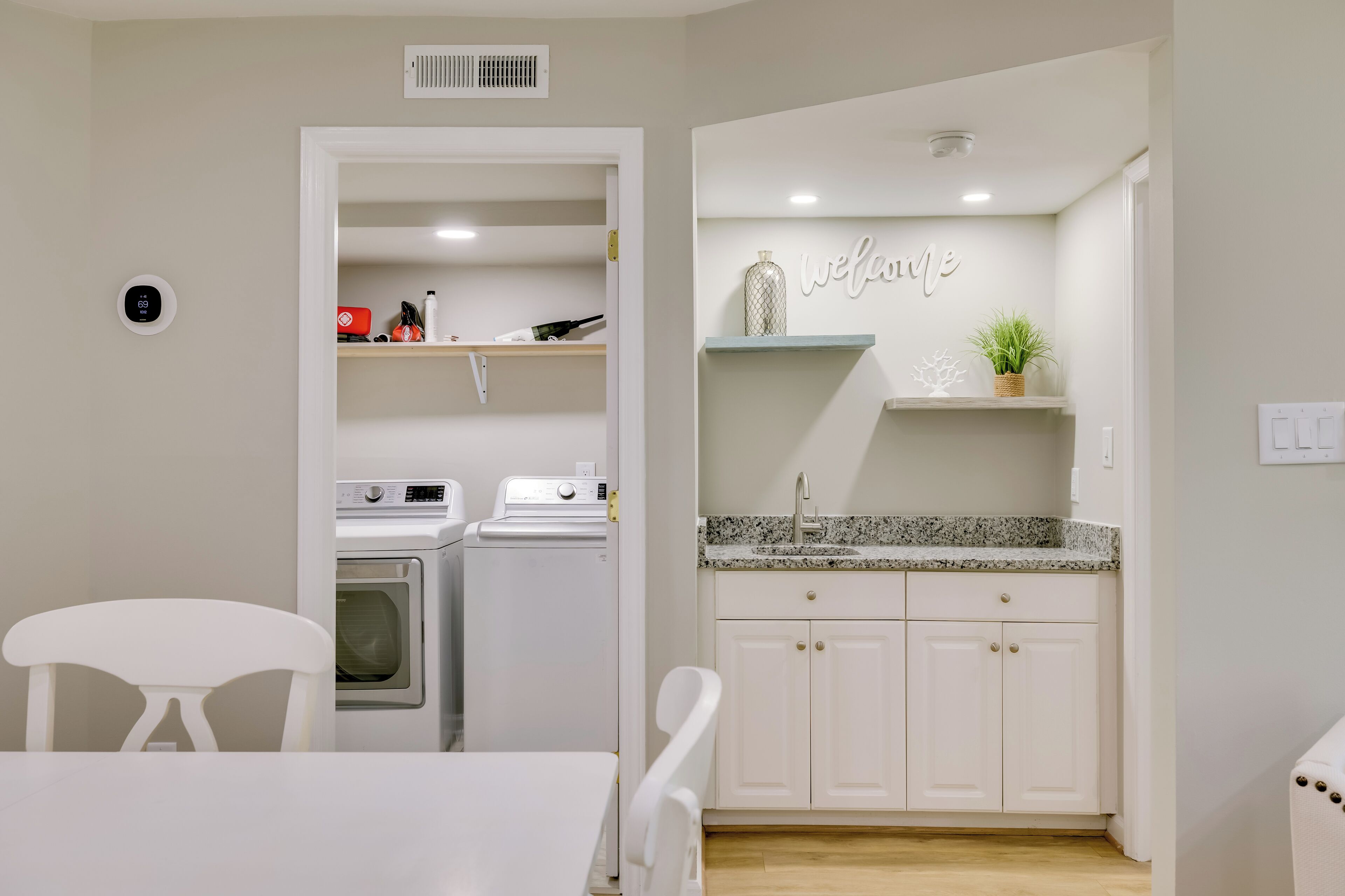 Cocina compacta con lavadora, un lavamanos y un cartel que dice 'welcome'.