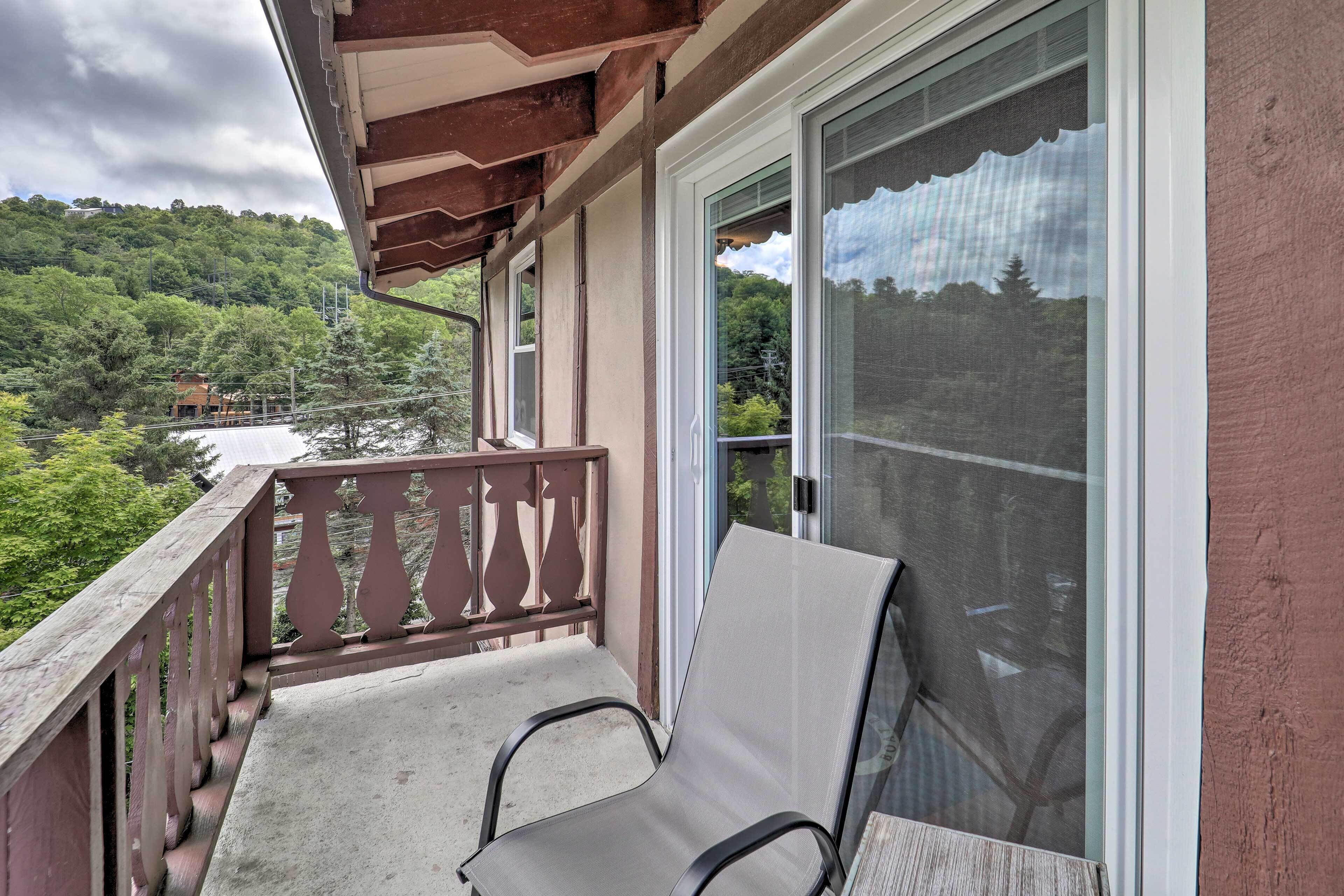 Un balcon avec une chaise, une table et une vue sur une zone boisée.