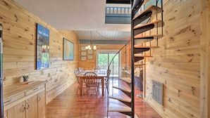 A wooden interior with a dining area, staircase, and kitchen.
