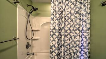 A bathroom with a shower, a towel rack, and a patterned shower curtain.