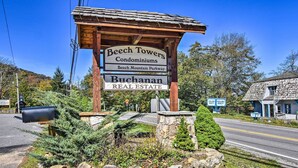 A wooden sign for Beech Towers Condominiums and Buchanan Real Estate, with a mailbox and landscaping in front.