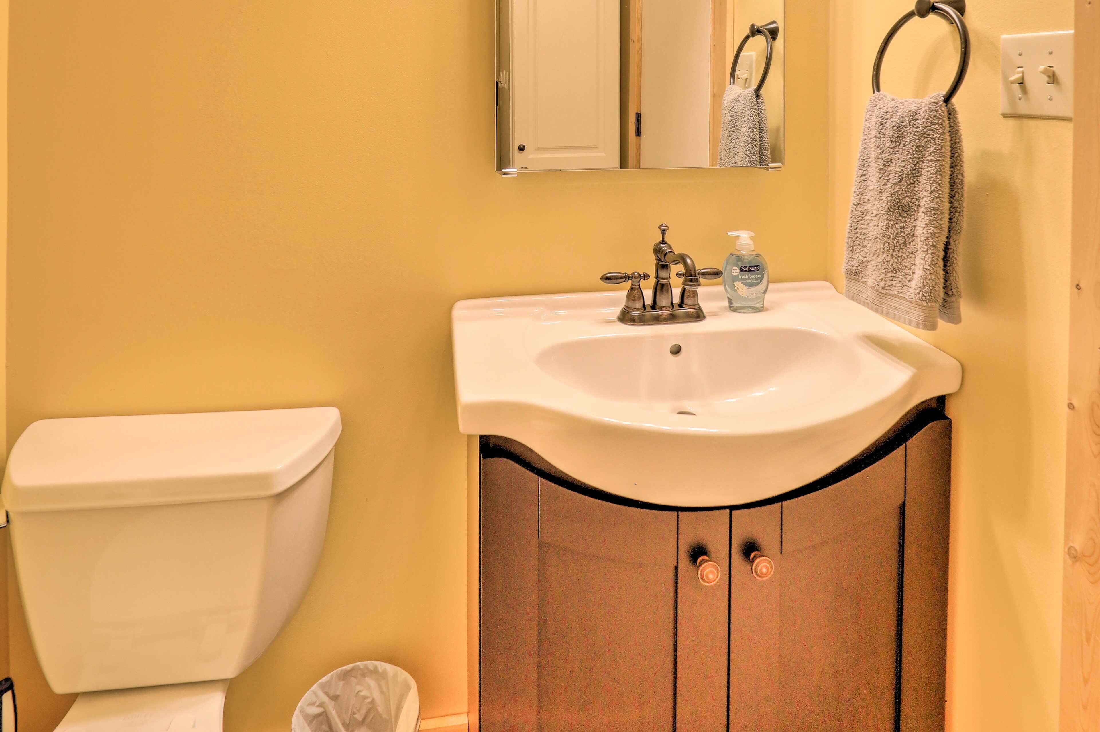 A bathroom with a white toilet, a sink with a mirror above it, and a towel hanging on a towel rack.
