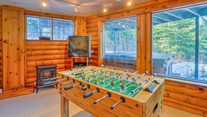 A cozy room with wooden walls, a foosball table, a television, and large windows offering a view of the outdoors. - Cabin w/ Hot Tub: 3 Mi to Main St Breckenridge! (Breckenridge)