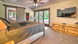 Ein Schlafzimmer mit einem Bett, einem Deckenventilator, einem Fernseher, einer Holzkommode und einer Schiebetür im Bauernhausstil.