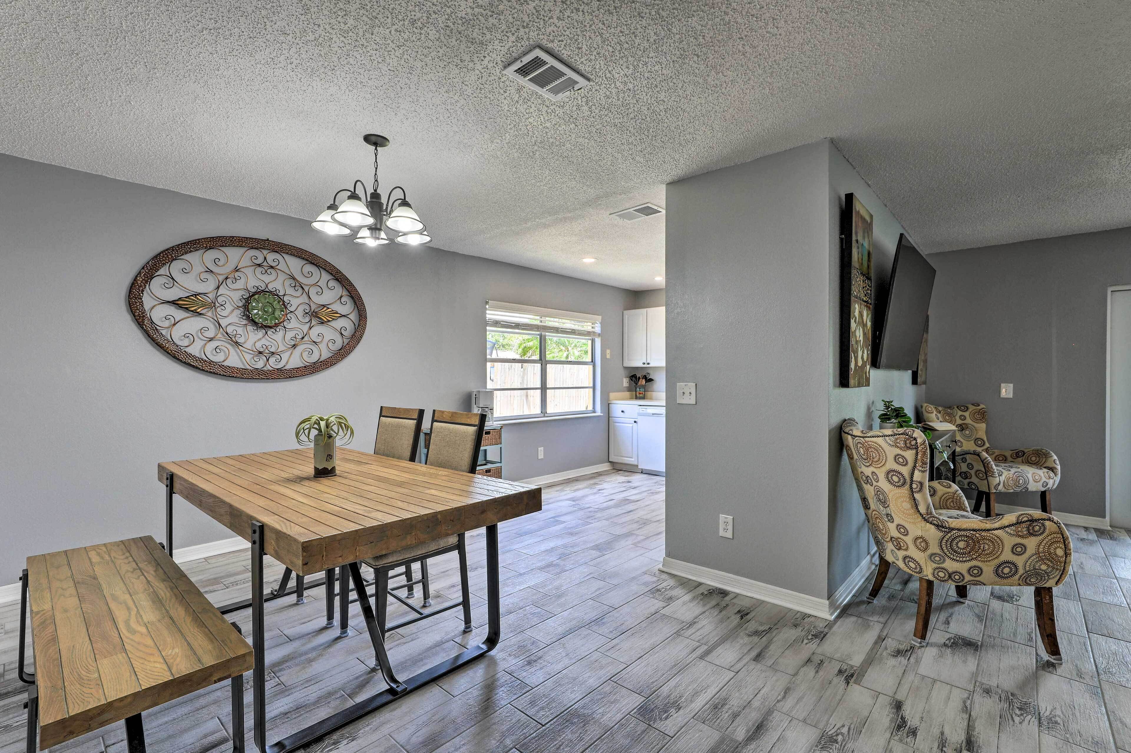 Un coin repas comprenant une table et des chaises en bois, un élément décoratif mural et un luminaire suspendu.