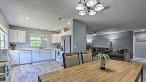 Una cocina moderna con armarios blancos, una mesa de comedor con sillas y una lámpara de techo.