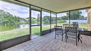 Un patio techado con vistas a un lago, mobiliario exterior y suelo de ladrillo.