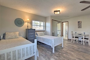 A bedroom with two beds, a dresser, a desk with chairs, and a window. - Bayfront Panama City Studio Near Tyndall Afb! (Panama City)