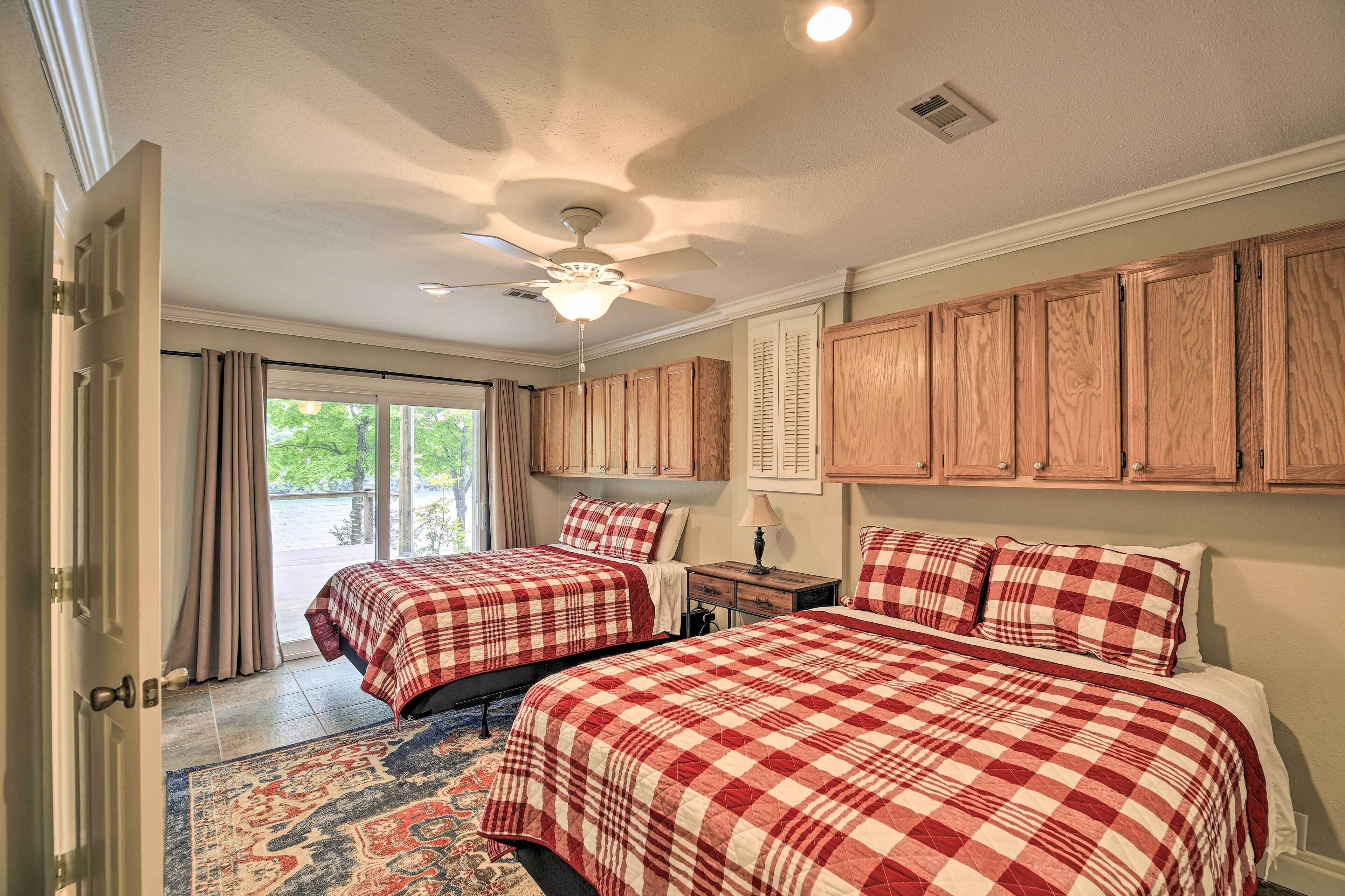 A bedroom with two beds, a ceiling fan, and wooden cabinets.